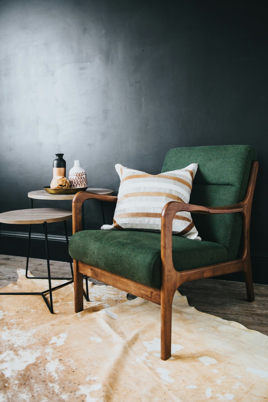 Green accent chair beside a pair of round side tables