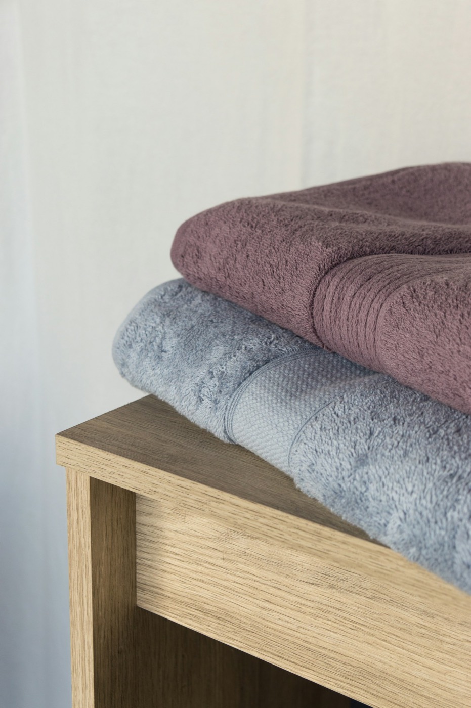 Folded bath towels stacked on a wooden table